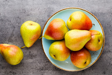 Fresh bio pear with leaves on the plate. Gray stone table.