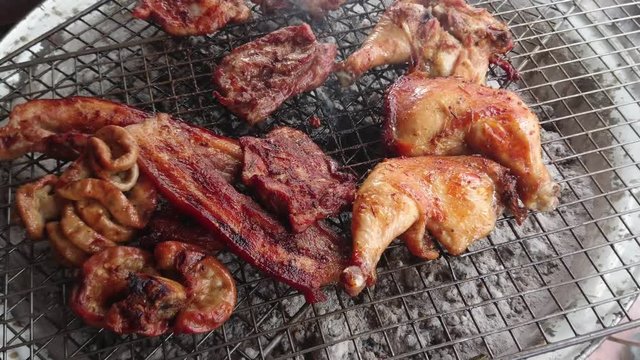 Assorted delicious grilled meat over the coals on a barbecue, top view