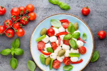 Delicious caprese salad with ripe cherry tomatoes and mini mozzarella cheese balls with fresh basil leaves.