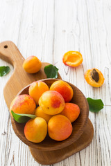 Ripe apricots and glass of juice in wooden bowl