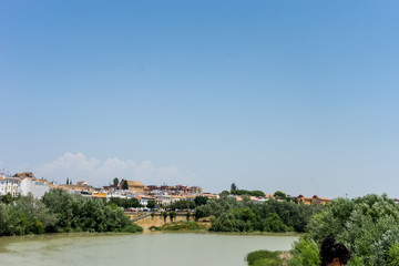 Fototapeta na wymiar Spain, Cordoba, SCENIC VIEW OF BUILDINGS AGAINST CLEAR BLUE SKY with guadalquivir river in foreground