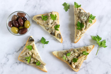 Triangular sandwiches with summer mushrooms cooked with cream and herbs served with olives.