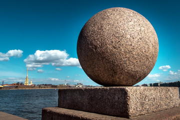 A granite ball is an element of the fencing of the Neva embankment on the background of the Peter and Paul Fortress. Stones St. Petersburg.