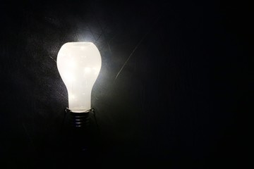 Glowing lightbulb on black background, idea concept