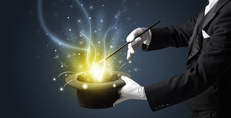 Magician hand conjure with wand  light from a black cylinder