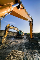 Fototapeta premium Zwei Bagger auf einer schlammigen Baustelle, Hochformat