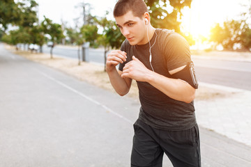 A young man fulfills blows on the street, morning training before Boxing, coach