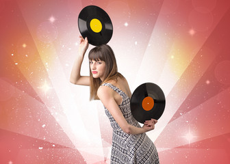 Young lady holding vinyl record on a red background with lights shining behind her