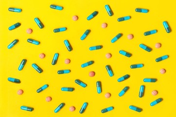 Capsule pills on yellow background. Top view of medicaments. 