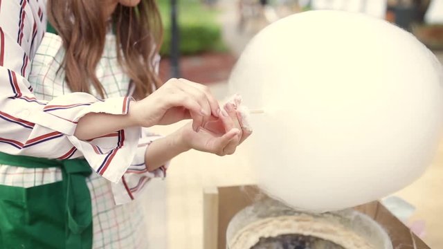 Video theme is a small business cooking sweets. Caucasian man Hands close-up of a street vendor making a candy floss of white color. In the summer in the park