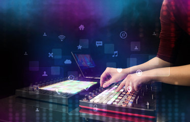 Hand mixing music on dj controller with social media concept icons
