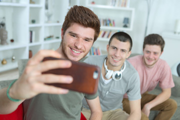Fototapeta premium Three young men taking self portrait photograph with cellphone