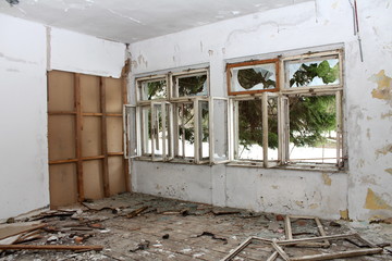 Room in abandoned building with broken windows, destroyed floorboards and dilapidated wall...