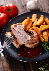 Meat chunks wrapped with bacon served with potato wedges