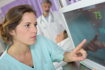 nurse monitoring patients heartbeat during surgery