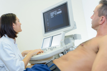 young female doctor using ultrasound scan on male patient