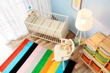 Modern interior of light cozy baby room with crib, view from above