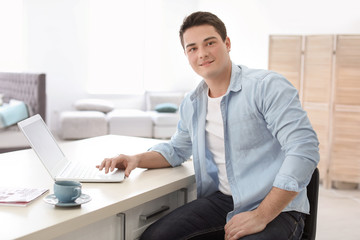 Fototapeta premium Portrait of confident young man with laptop at table
