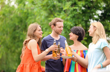 Young people with bottles of beer and food outdoors. Summer barbecue