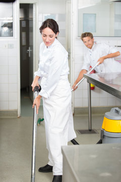 Man and woman cleaning floor in profesional kitchen