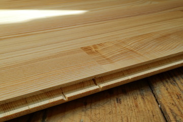 An image of an old wooden floor and a new parquet board.