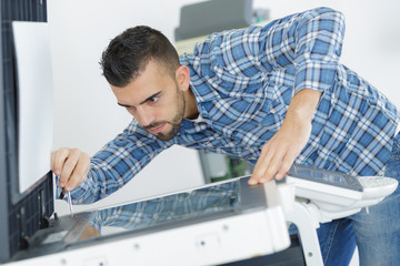 Obraz premium young male technician repairing digital photocopier machine