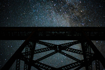 The Milkyway galaxy shining bright over an abandoned railway trestle in the midwest  - obrazy, fototapety, plakaty