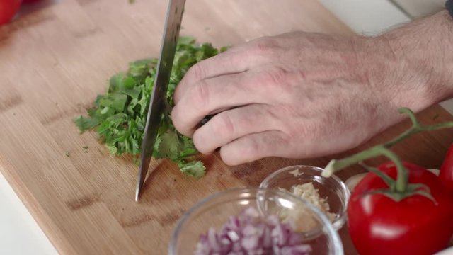Chef chopping cilantro on cutting board
