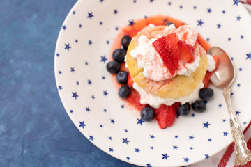 Homemade Strawberry and Blueberry Shortcake in White Bowl with Blue Stars; Red and White Striped Towel; Blue Background