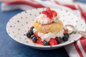 Homemade Strawberry and Blueberry Shortcake in White Bowl with Blue Stars; Red and White Striped Towel; Blue Background