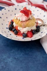 Homemade Strawberry and Blueberry Shortcake in White Bowl with Blue Stars; Red and White Striped Towel; Blue Background