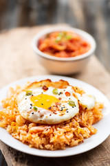 Kimchi fried rice with fried egg on top and fresh kimchi cabbage in a bowl, Korean food