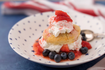 Homemade Strawberry and Blueberry Shortcake in White Bowl with Blue Stars; Red and White Striped Towel; Blue Background