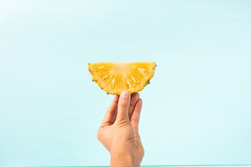 Slice pineapple holding by hand for eating on green background, tropical fruit