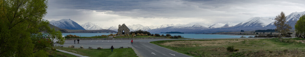 Wide panoramic view including the Church of the Good Shepherd in front of Lake Tekapo and the snow covered Southern Alps.