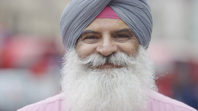 Portrait of Indian man in a turban smiling to camera, in slow motion