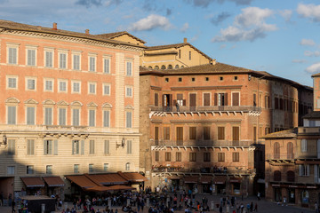 Obraz premium Square corner with medieval buildings in Siena, Italy, against a blue sky with clouds at sunset