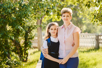 happy mom and daughter schoolgirl with backpack outdoors