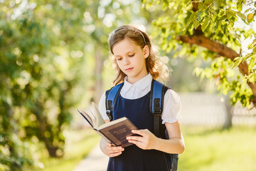 Fototapeta premium schoolgirl reads book outdoors