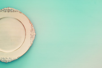 Top view of vintage white empty plate over blue mint wooden background. Flat lay
