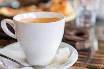 close up of white cup of cappuccino on table