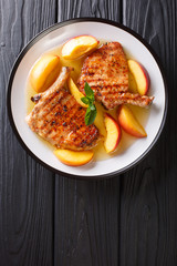 grilled pork chop with glazed peaches and honey garlic sauce close-up on a plate. Vertical top view from above