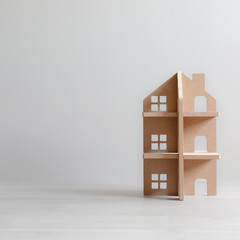 Three-storey wooden toy house in bright room with copy space. Symbol of real estate, construction and development