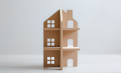 Toy wooden house on white wooden floor and bright background. Concept of family, welfare and development. Copy space.