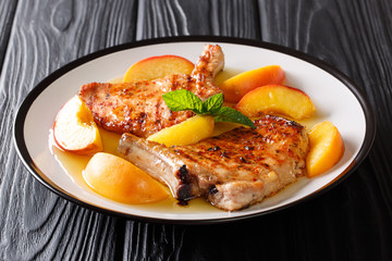 French recipe grilled spicy pork with peaches, honey garlic sauce and mint closeup on a plate. horizontal