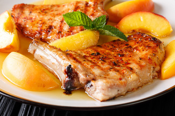 Delicacies: the grilled pork chop is served with glazed peaches and mint closeup. horizontal