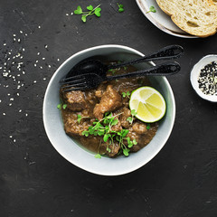 Homemade beef casserole served with rice, with juicy lime and micro greens portioned. Top View
