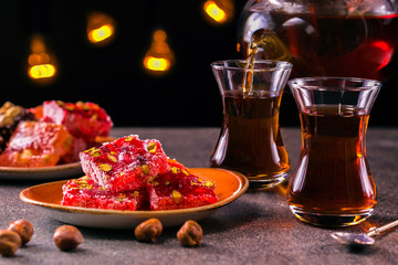 Turkish tea in traditional glass and plate with rahat lokum. Istanbul cafe with oriental culture of the street food.Evening time.