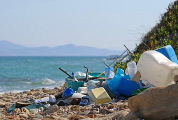 plastic garbage and wastes on the beach with the sea and an island on background