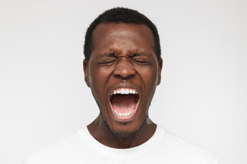 Close up portrait of screaming with closed eyes crazy african american man in blank white t-shirt...